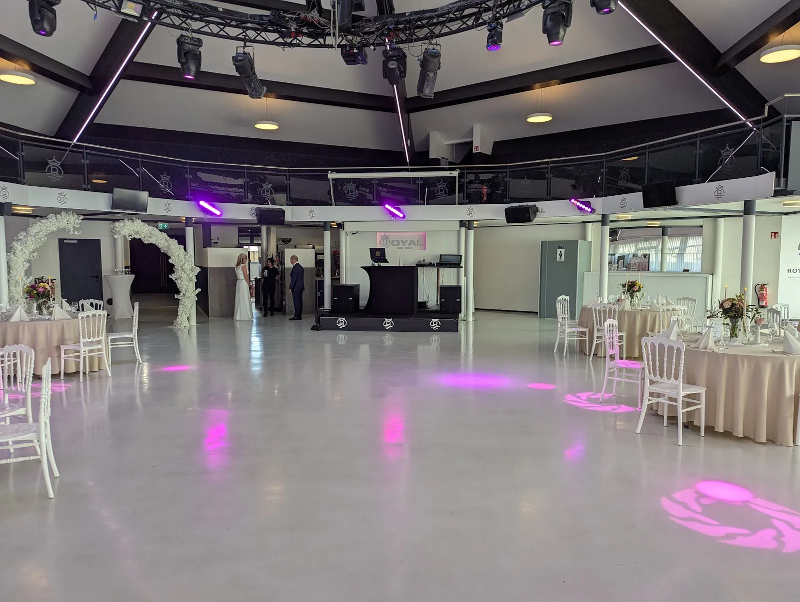 Saal im Royal am See vor der Hochzeit mit Blumenbögen, DJ-Pult und Gobo-Projektionen auf dem Boden