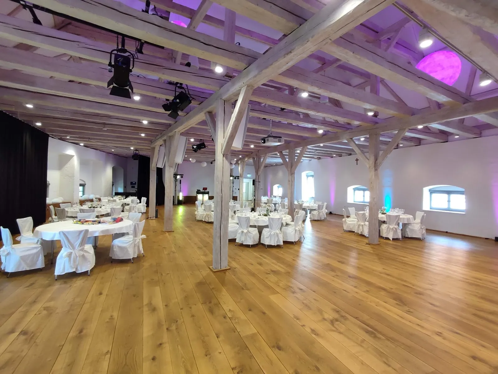 Festsaal im Wittelsbacher Schloss Friedberg mit weißen Holzbalken, Holzboden und eingedeckten Tischen
