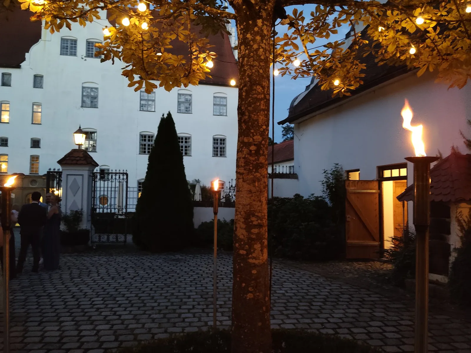Zufahrt zu Schloss Neuburg an der Kammel im Abendlicht mit Fackeln