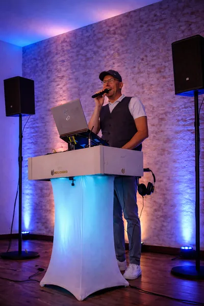 DJ Rico Cinsano mit Mikrofon am DJ-Pult