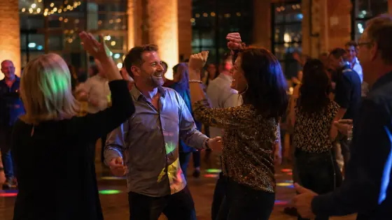 Tanzende Paare in einer Industrieloft-Halle mit Backstein, DJ für Geburtstag