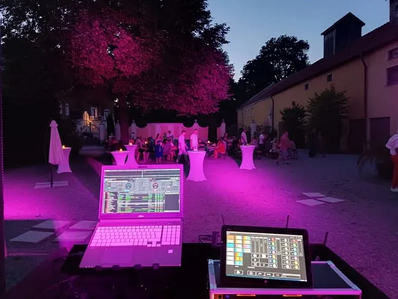 DJ-Pult mit Lichttechnik im Innenhof des Gut Schwabhof in der Dämmerung bei einer Firmenfeier