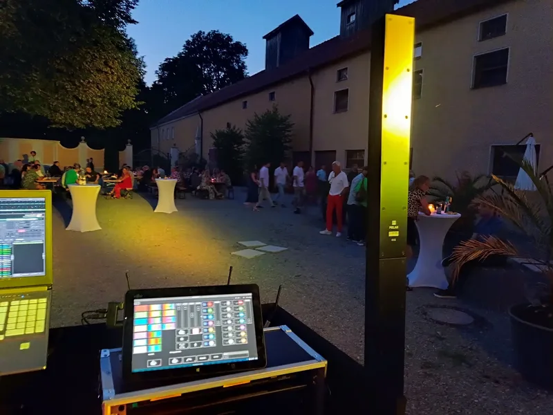DJ-Pult im Innenhof des Gut Schwabhof bei einer Firmenfeier in der Dämmerung mit Stehtischen