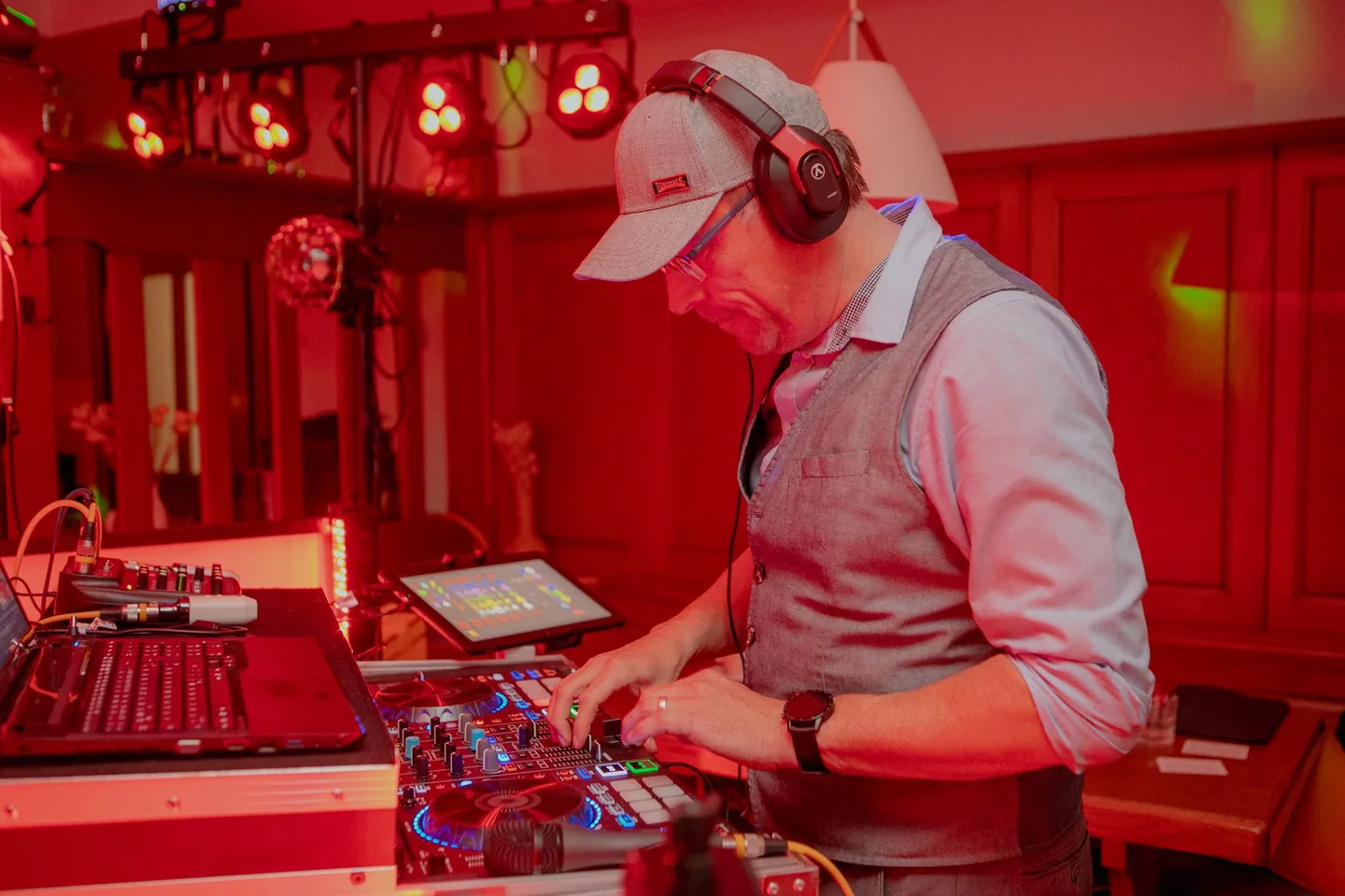 DJ Rico Cinsano mit Kappe und Kopfhörer am DJ-Controller im roten Licht