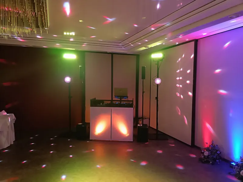 DJ-Pult im Saal mit Partylicht an der Wand