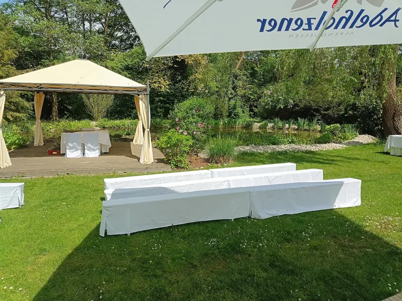 Pavillon mit weiß bezogenen Bänken im Park des Parkhotels Schmid