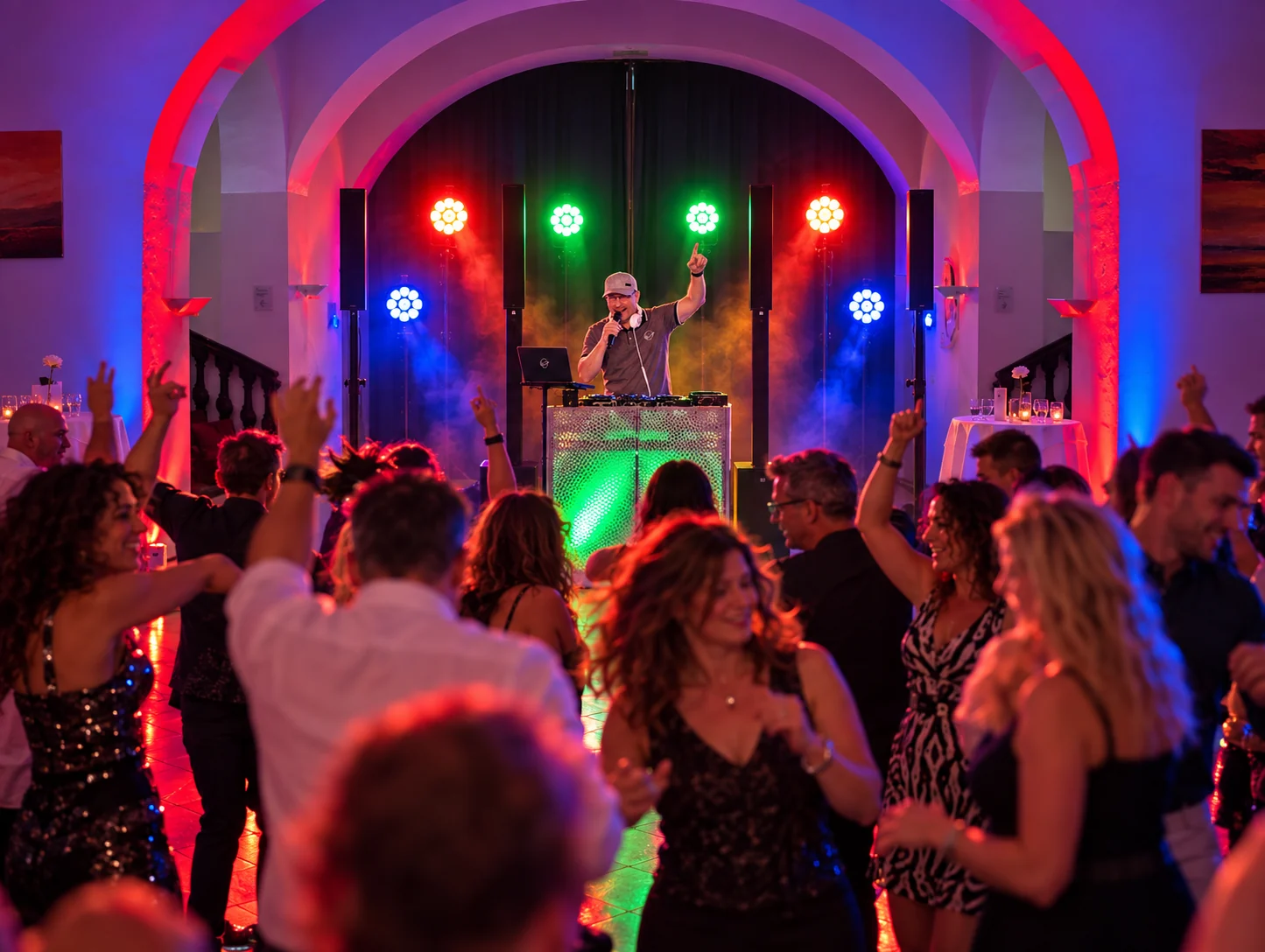 DJ Rico Cinsano mit Mikrofon, DJ-Pult und Lichttechnik während einer Party