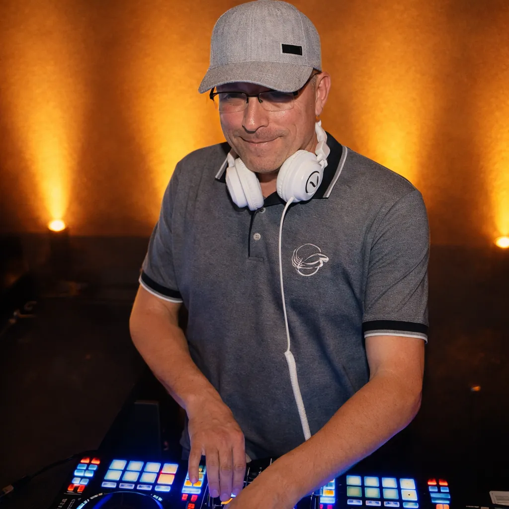 DJ Rico Cinsano mit weißen Kopfhörern um den Hals am DJ-Controller vor orange beleuchteter Wand