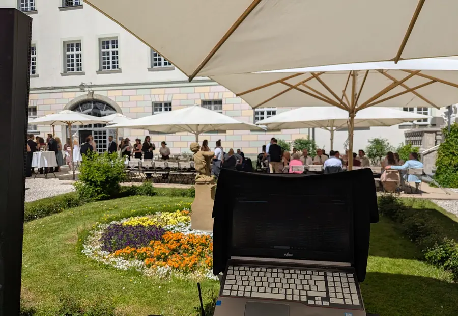DJ Blick auf eine Hochzeitsgesellschaft im Schlossgarten bei Sommerwetter