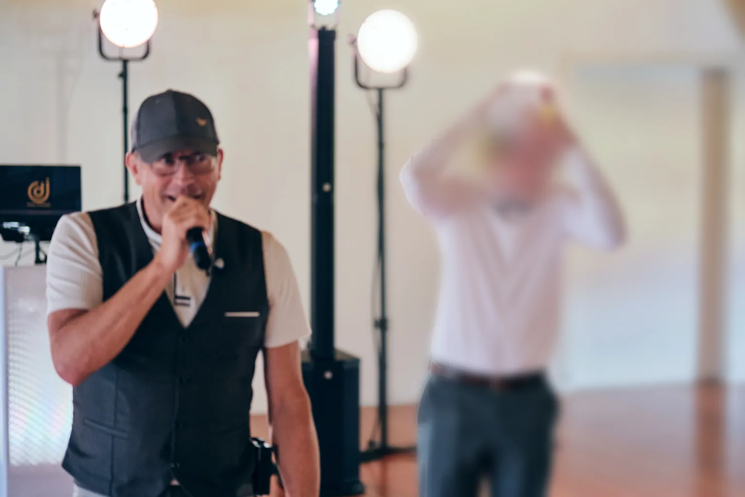 DJ Rico Cinsano moderiert mit Mikrofon, während der Bräutigam beim Brautverziehen eine Hahnenkamm-Mütze aufsetzt