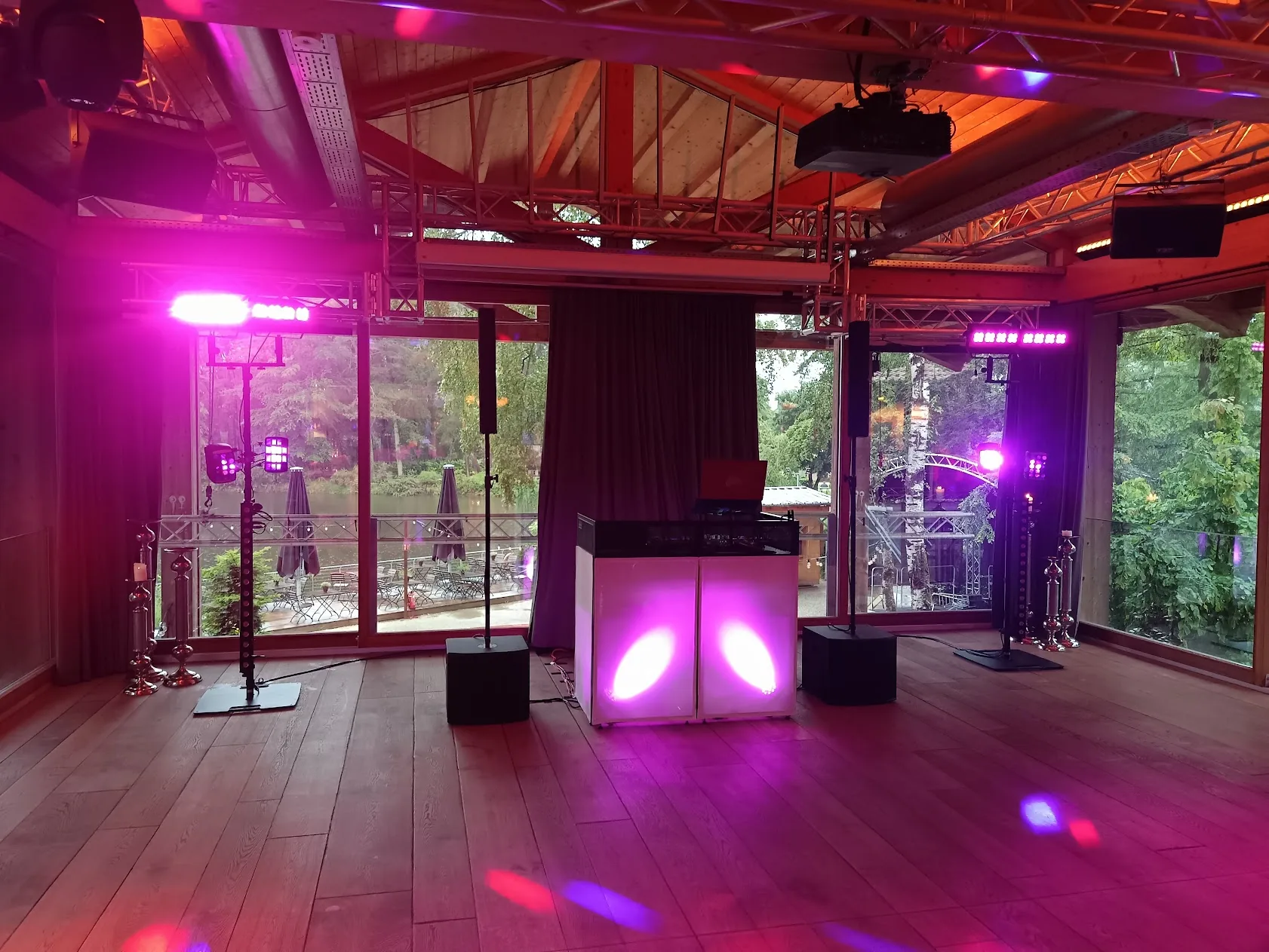 Beleuchtetes DJ-Pult im Saal der Birkenheide, dahinter die Fensterfront zum See