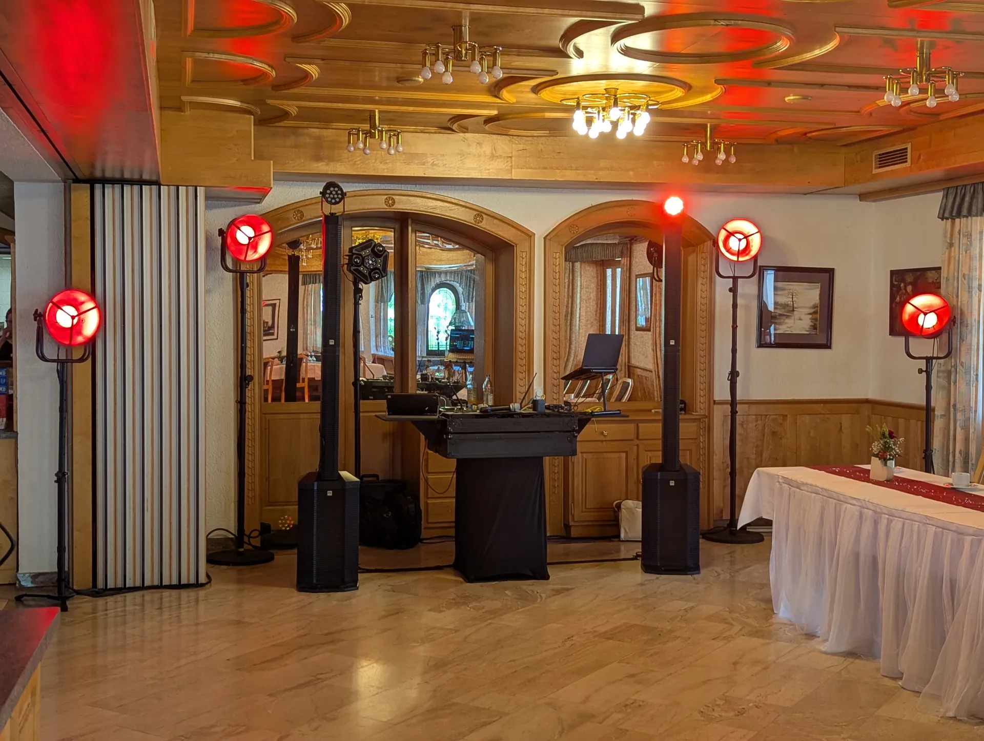 DJ-Pult im holzvertäfelten Saal des Fischerwirt, ringsum Scheinwerfer im Retro-Design mit rotem Licht
