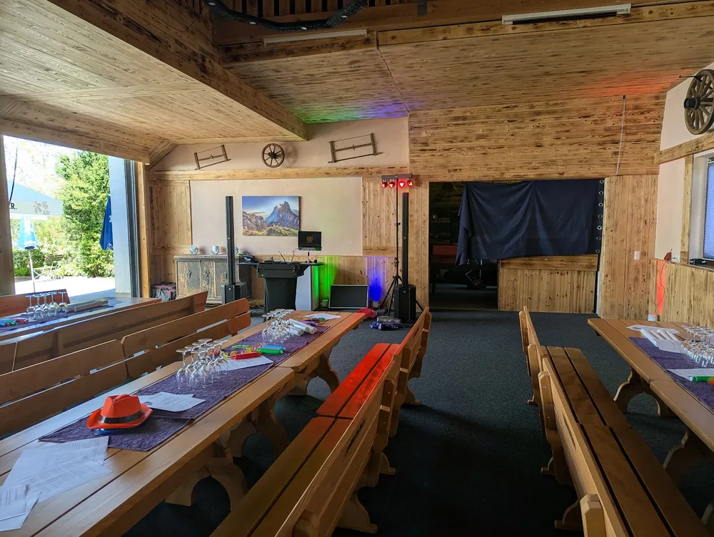Stadel des Fischerwirt mit Holzbänken, langen Tischen und kleinem DJ-Aufbau im Hintergrund