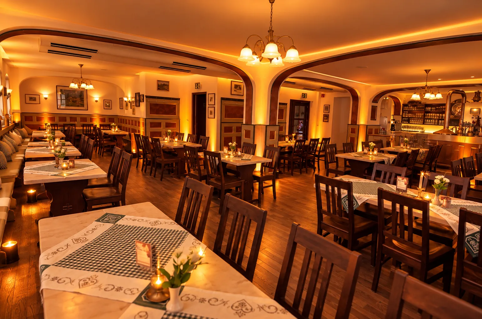 Gaststube im Gasthaus Daniel in Ingolstadt am Abend: Holzboden, eingedeckte Tische mit Kerzen, Rundbögen und im Hintergrund der Tresen der Hausbrauerei