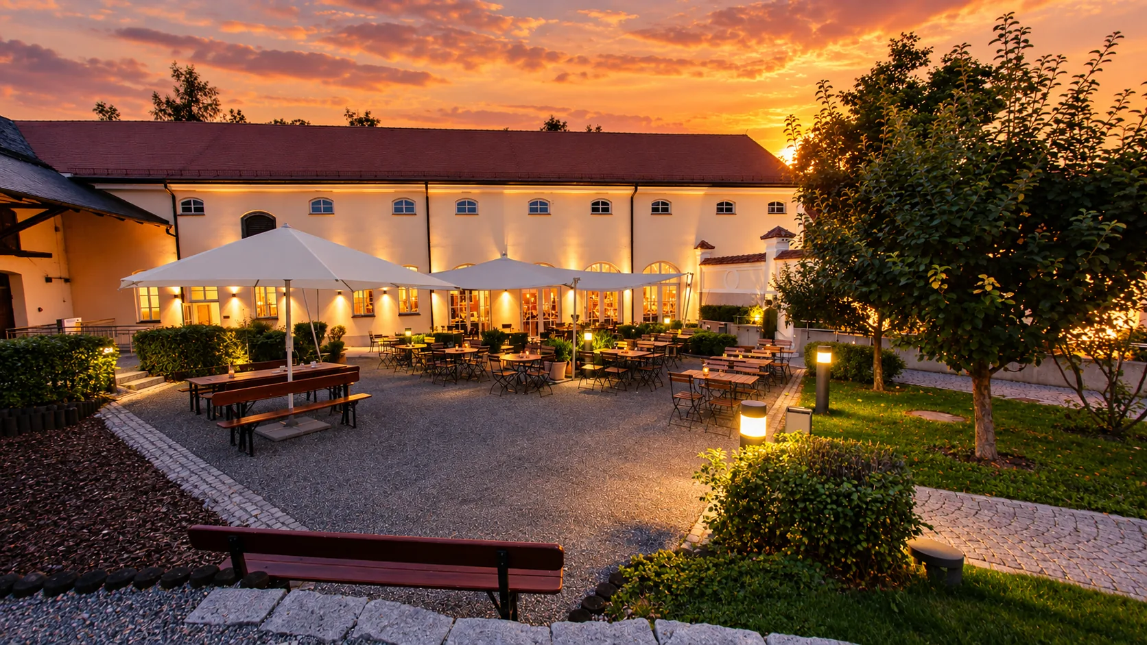 Innenhof des Kloster Holzen am Abend, beleuchtete Fassade und Biergarten mit Sonnenschirmen