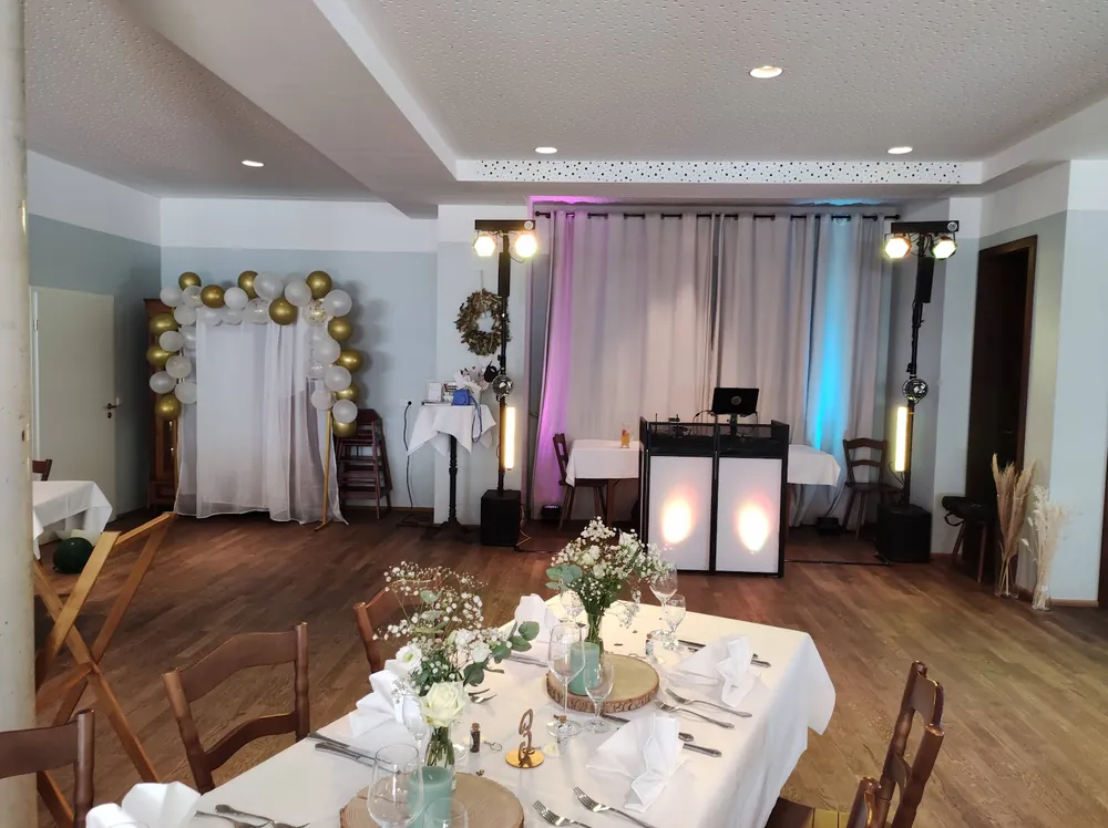 DJ-Aufbau im Landhausbräu Koller neben einem Ballonbogen, Tische im Vordergrund