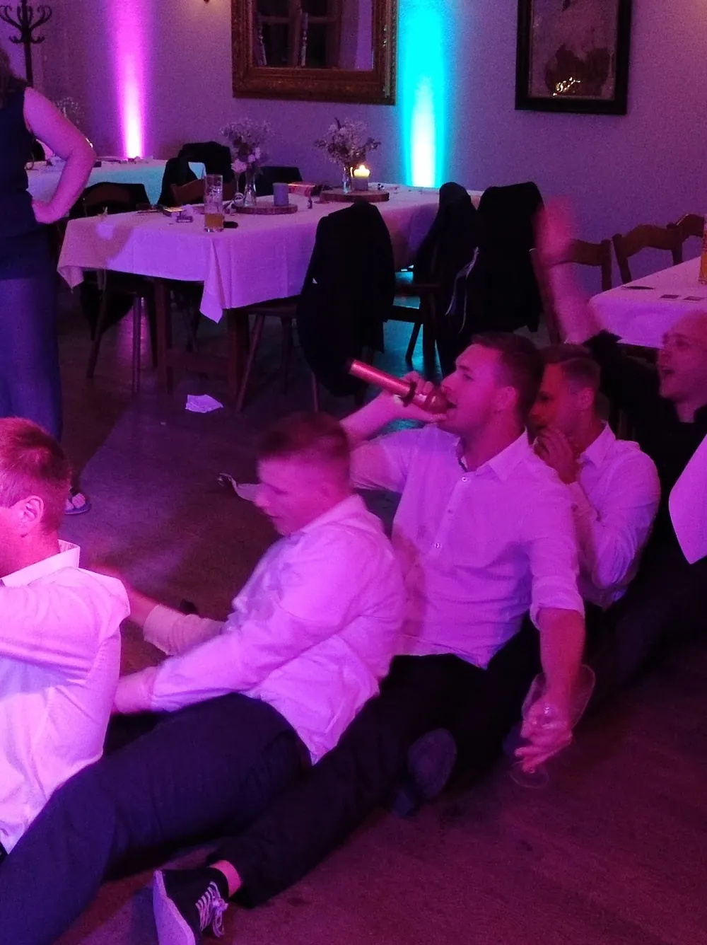 Gäste sitzen am späten Abend auf der Tanzfläche und singen ins Mikrofon