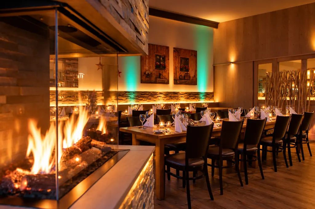 Restaurant der Schlemmerhütte mit verglastem Kamin und langer Tafel