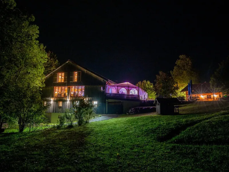 Berghof Riesen Rettenberg bei Nacht mit leuchtendem Festzelt und Hochzeitsfeier