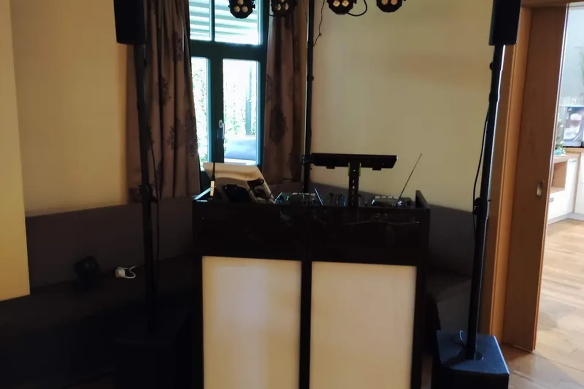 DJ-Setup mit schwarzem Pult und weißen Paneelen im Veranstaltungsraum beim Soundcheck – Hochzeits-DJ Rico Cinsano