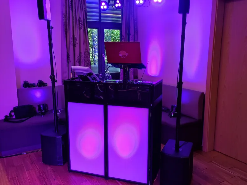 DJ-Setup von der Seite mit pinkfarbenem Raumlicht und Lichtstativen – Hochzeits-DJ Rico Cinsano