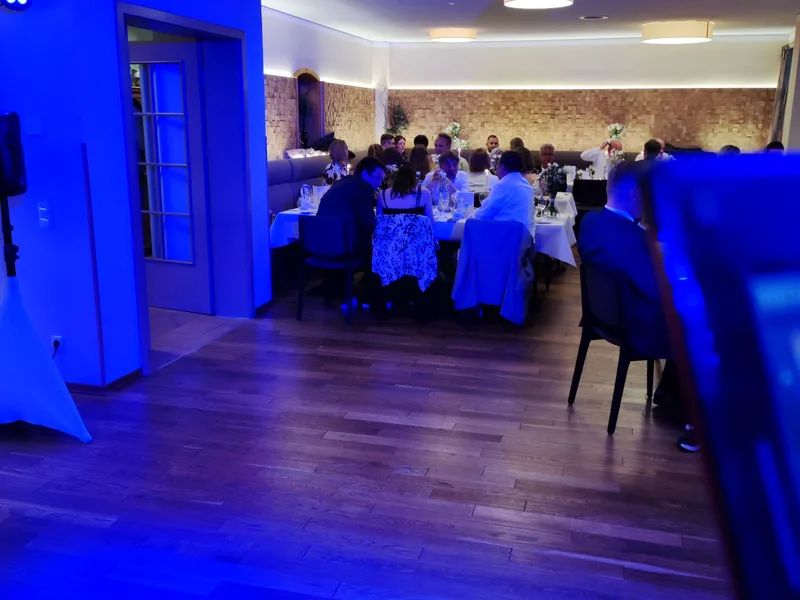 Hochzeitsgesellschaft beim Dinner im festlich beleuchteten Saal mit blauem Uplighting – Hochzeits-DJ Rico Cinsano