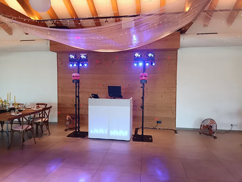 DJ-Setup von DJ Rico Cinsano im Grafenstadl – weißes DJ-Pult mit Partybeleuchtung vor Holzwand, Lichterdach und Tüllvorhang