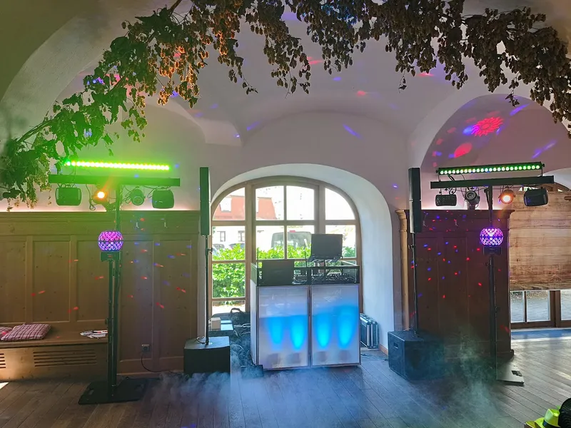 DJ-Setup von DJ Rico Cinsano in der Klosterschenke Scheyern – weißes DJ-Pult mit bunter Partybeleuchtung unter Hopfengewölbe