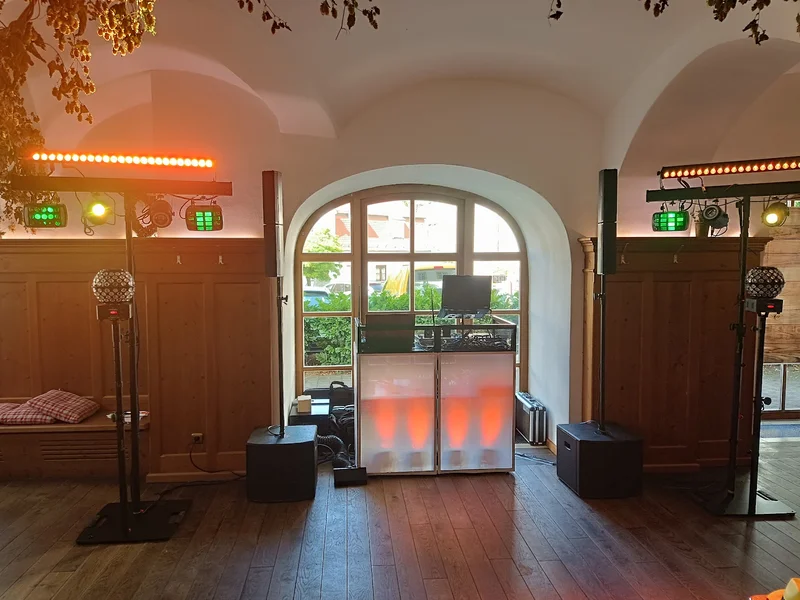 DJ-Setup Klosterschenke Scheyern – weißes DJ-Pult mit orangem Uplighting unter historischem Gewölbebogen