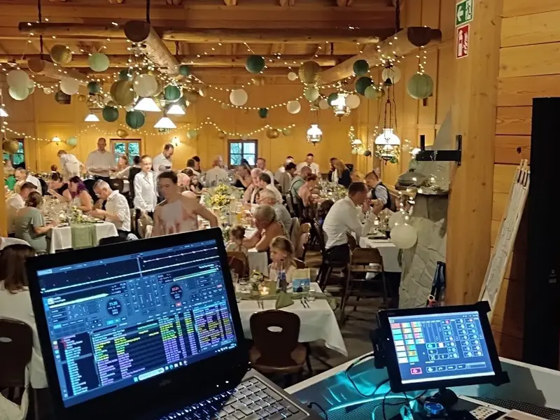 DJ-Ansicht auf den vollen Hochzeitssaal der Sonnenkopfhütte beim Abendessen