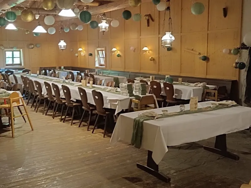 Hochzeitssaal der Sonnenkopfhütte mit langer Tafel, Lampions und offenem Steinkamin