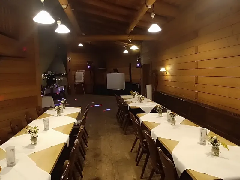 Hochzeitstafeln im Innenraum der Sonnenkopfhütte mit Married-Banner und Galerieebene
