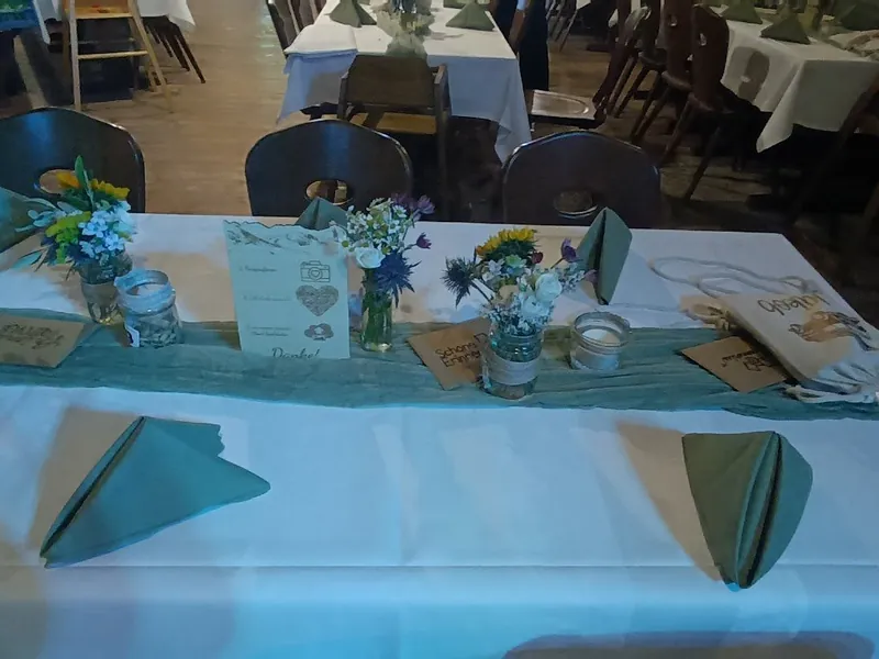 Brauttisch in der Sonnenkopfhütte mit Blumendekoration und grünen Servietten