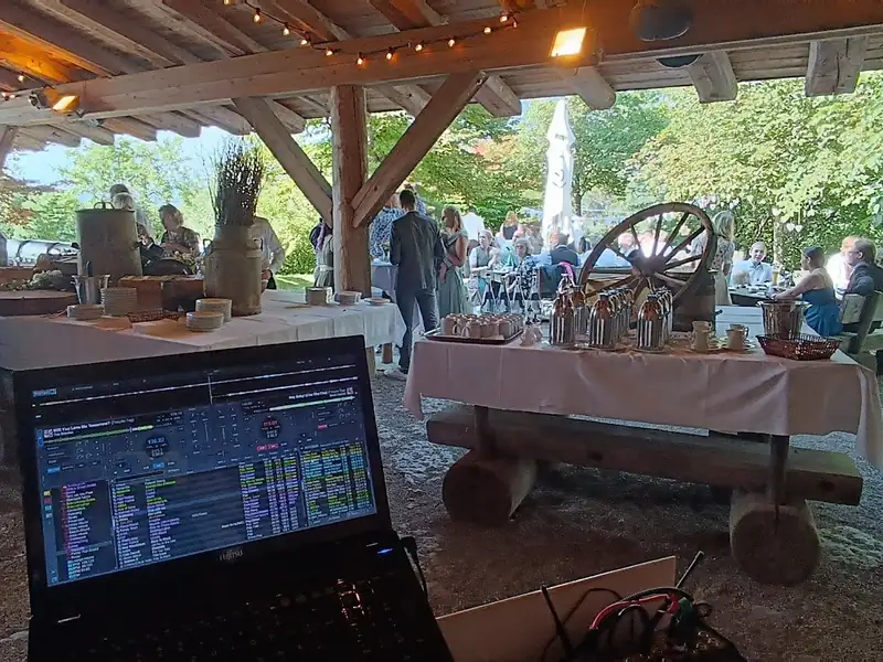 DJ-Perspektive auf den Buffet-Bereich im Außenbereich der Sonnenkopfhütte mit Wagenrad-Deko