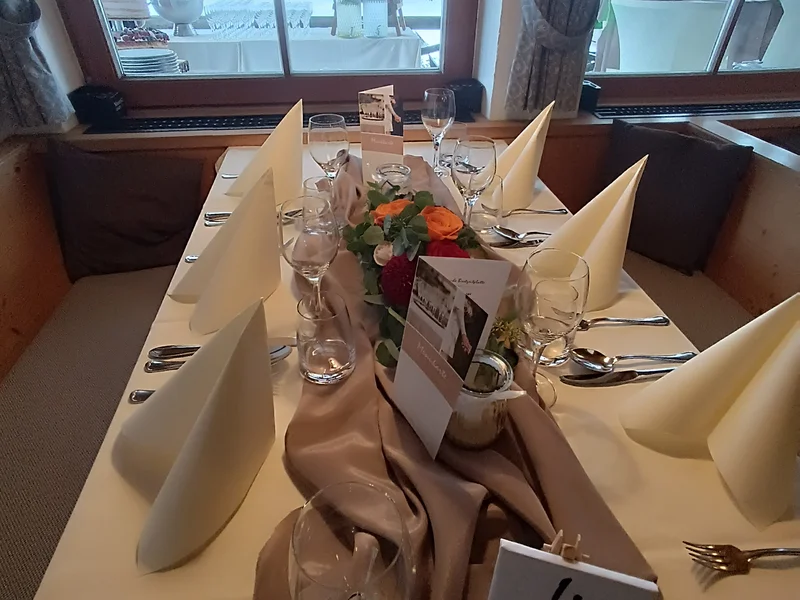Hochzeitstafel Stögeralm mit Blumengesteck und Fensterblick auf den Außenbereich