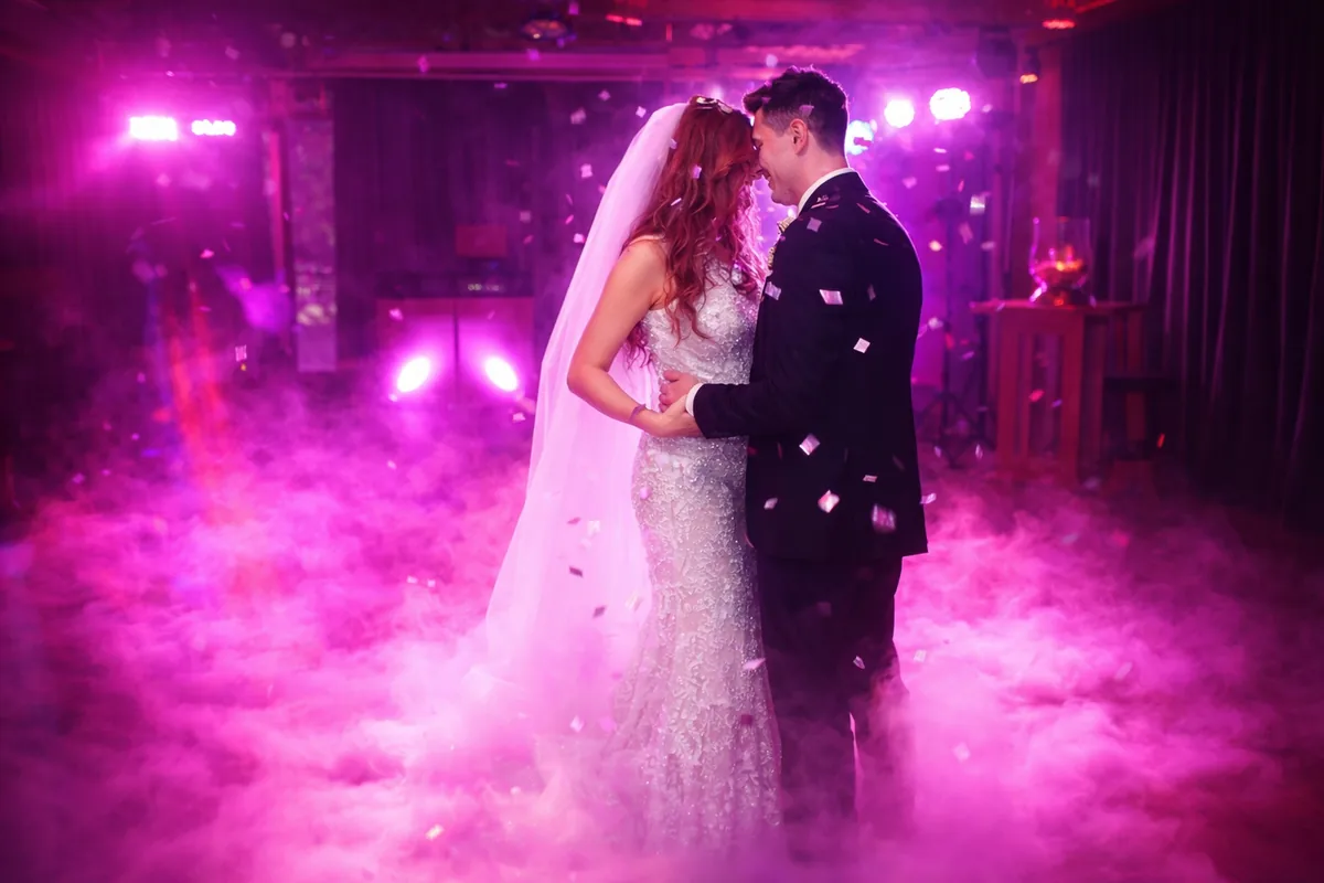 Brautpaar beim Hochzeitstanz auf tiefem Nebel in pinkem Licht