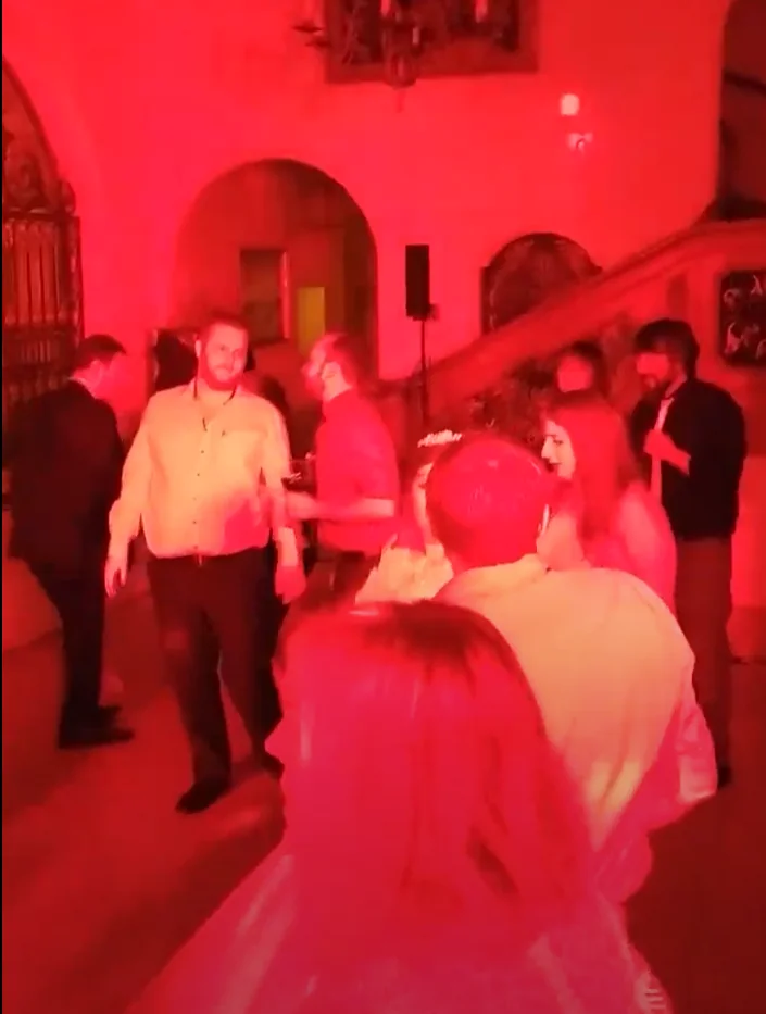 Tanzende Hochzeitsgäste im roten Licht vor der Treppe im Schloss Höhenried