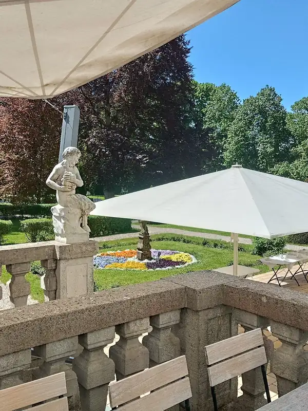 Schlossterrasse mit Sonnenschirmen und Blick auf den Schlosspark