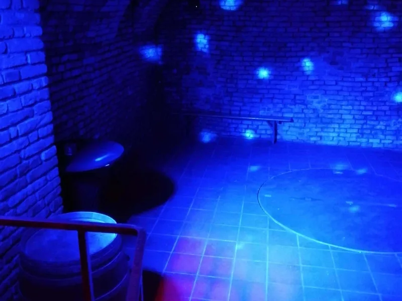 Gewölberaum des Zisternenkellers mit blauer Lichtstimmung und Bar